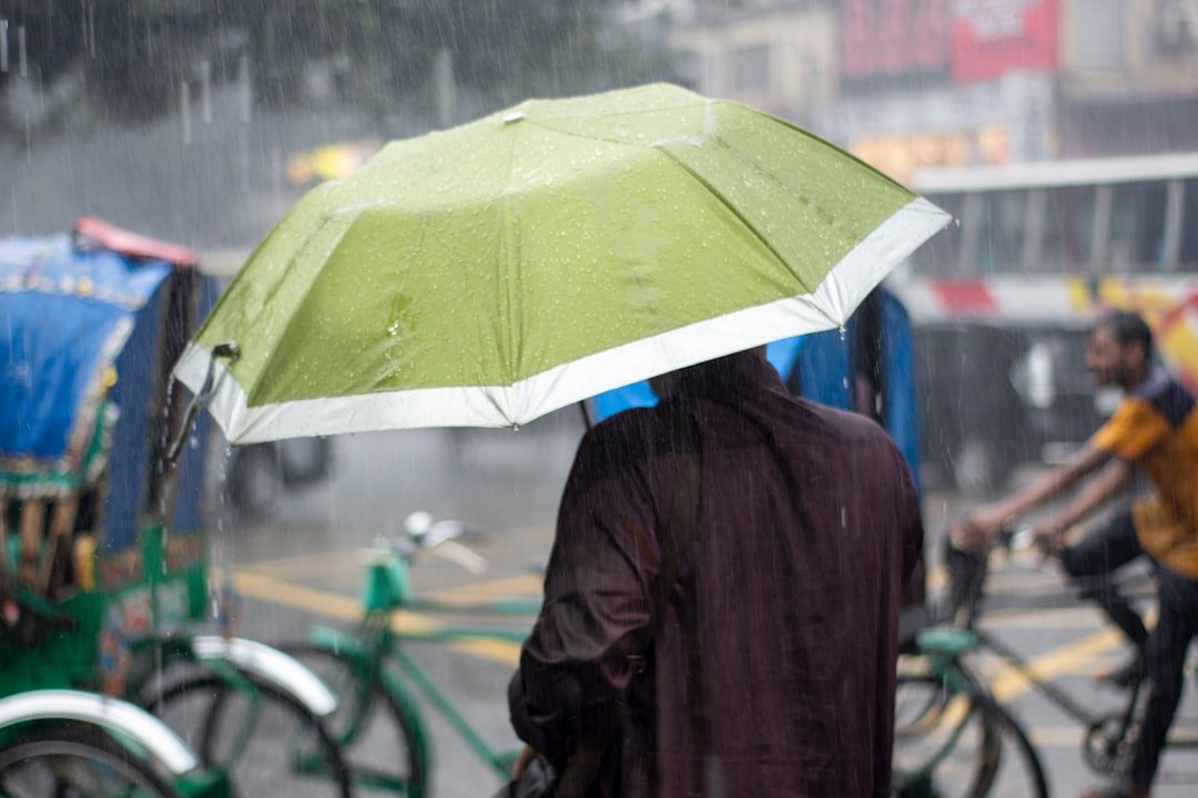 Person using compact umbrella on rainy city street