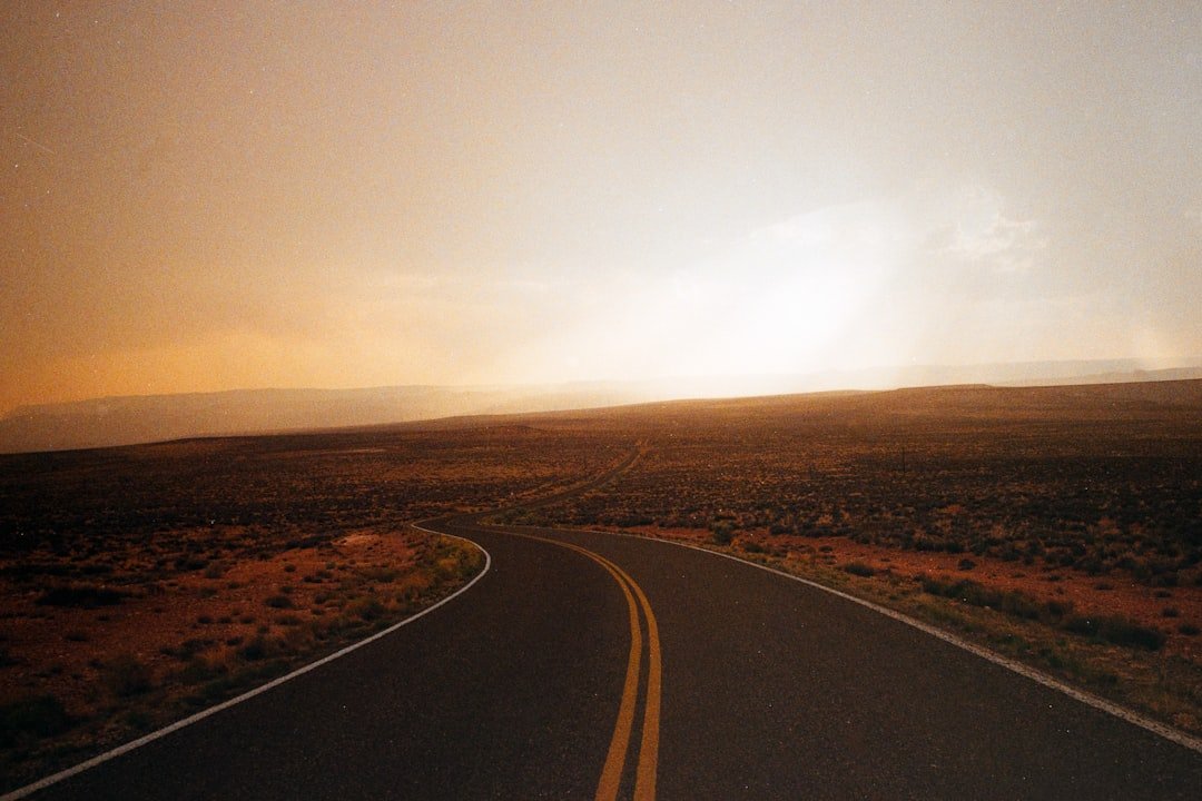 Desert road trip at sunset with long empty highway stretching toward mountains