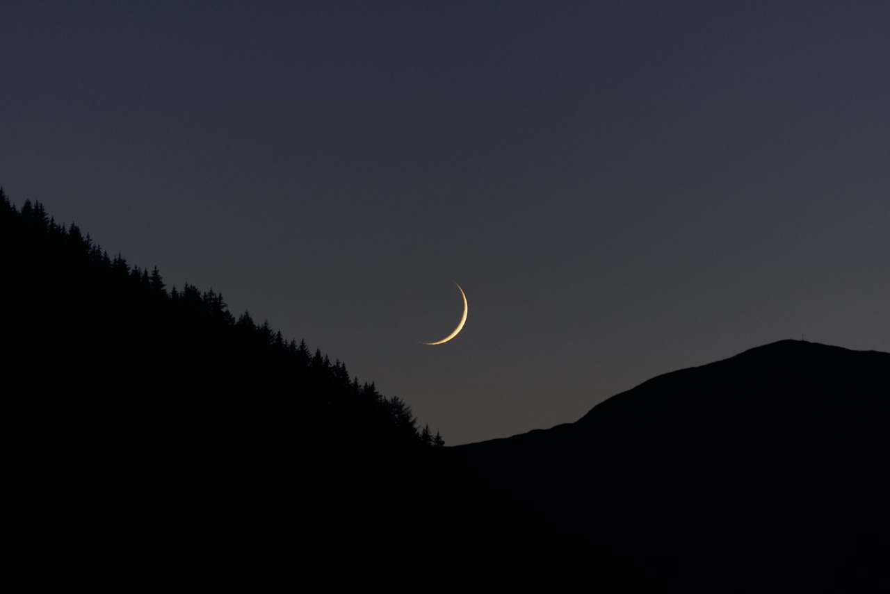 Crescent moon over mountain landscape
