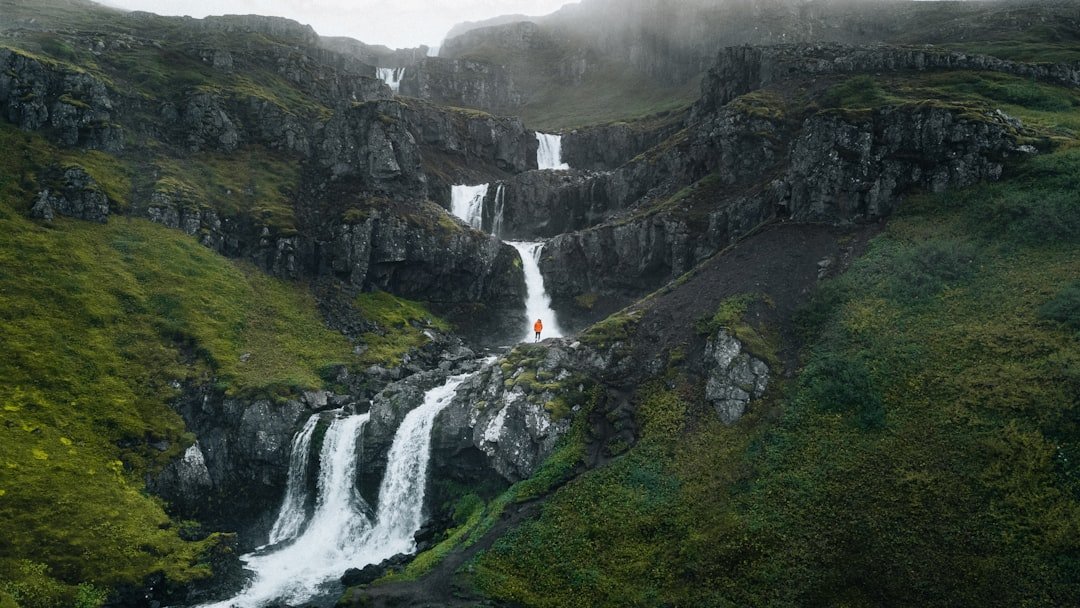 Hiker in rain jacket at waterfall