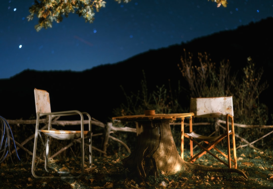 Family sitting in camping chairs under stars
