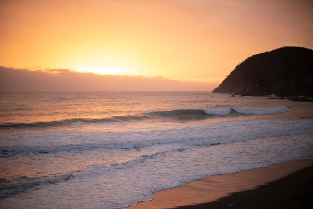 Golden sunrise over a wide sandy beach with gentle waves