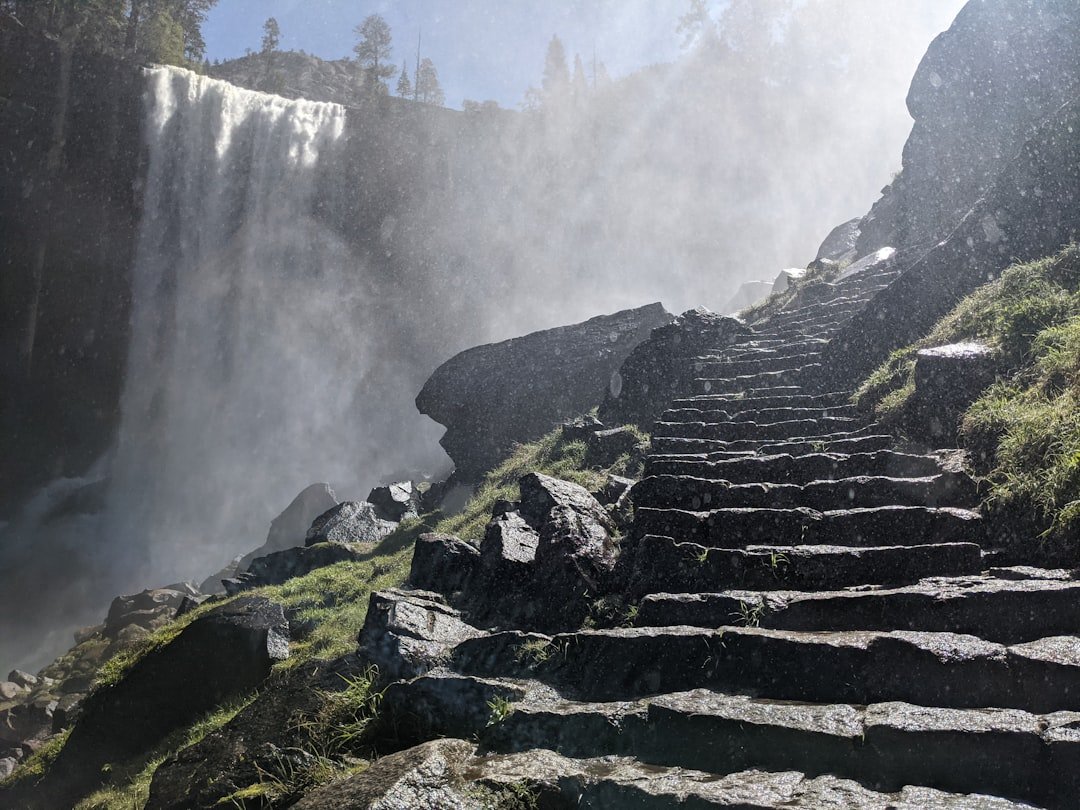 Hiker navigating misty trail near waterfall