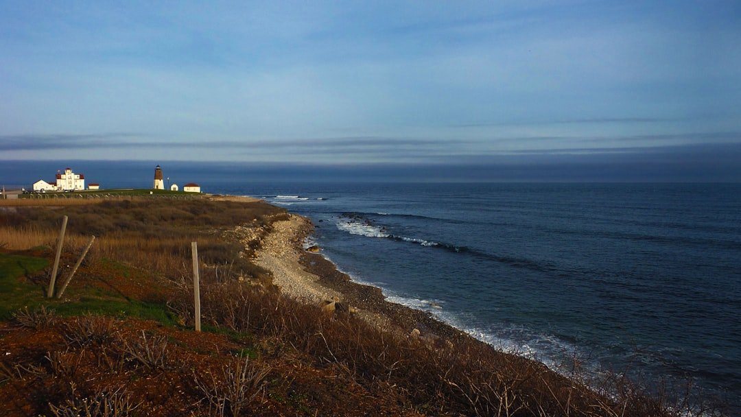 Rhode Island coastal lighthouse overlooking rocky shoreline and ocean