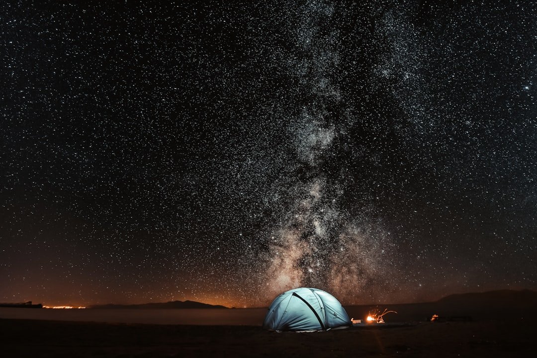 Camping tent illuminated under a canopy of stars at night