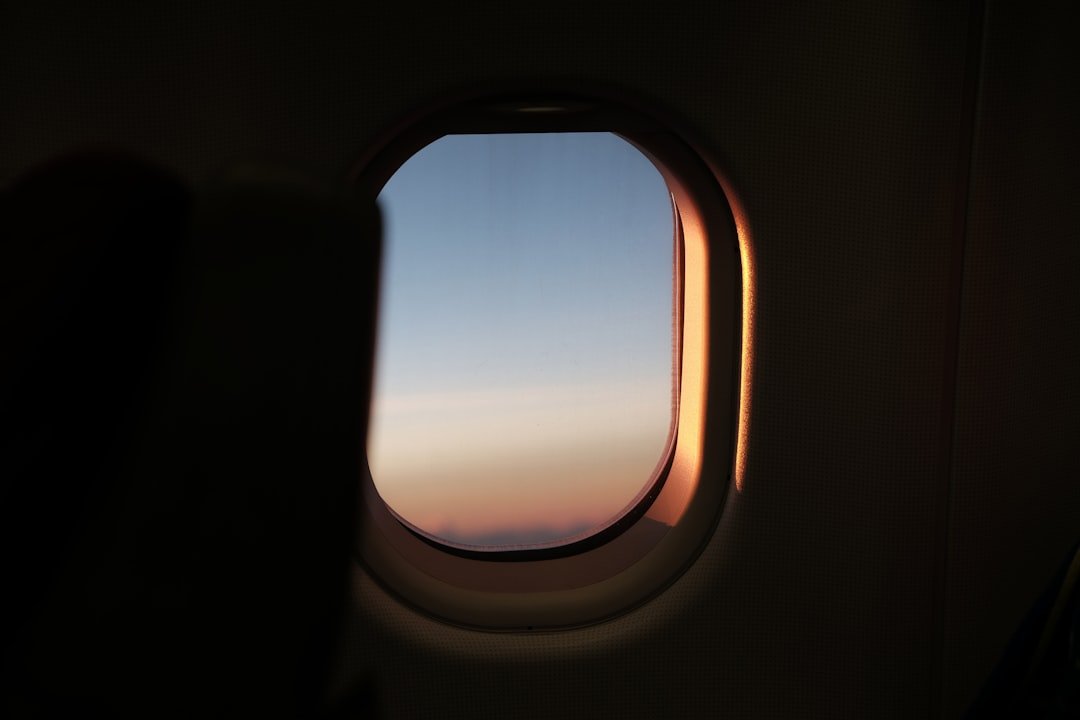 Person resting against airplane window during long flight