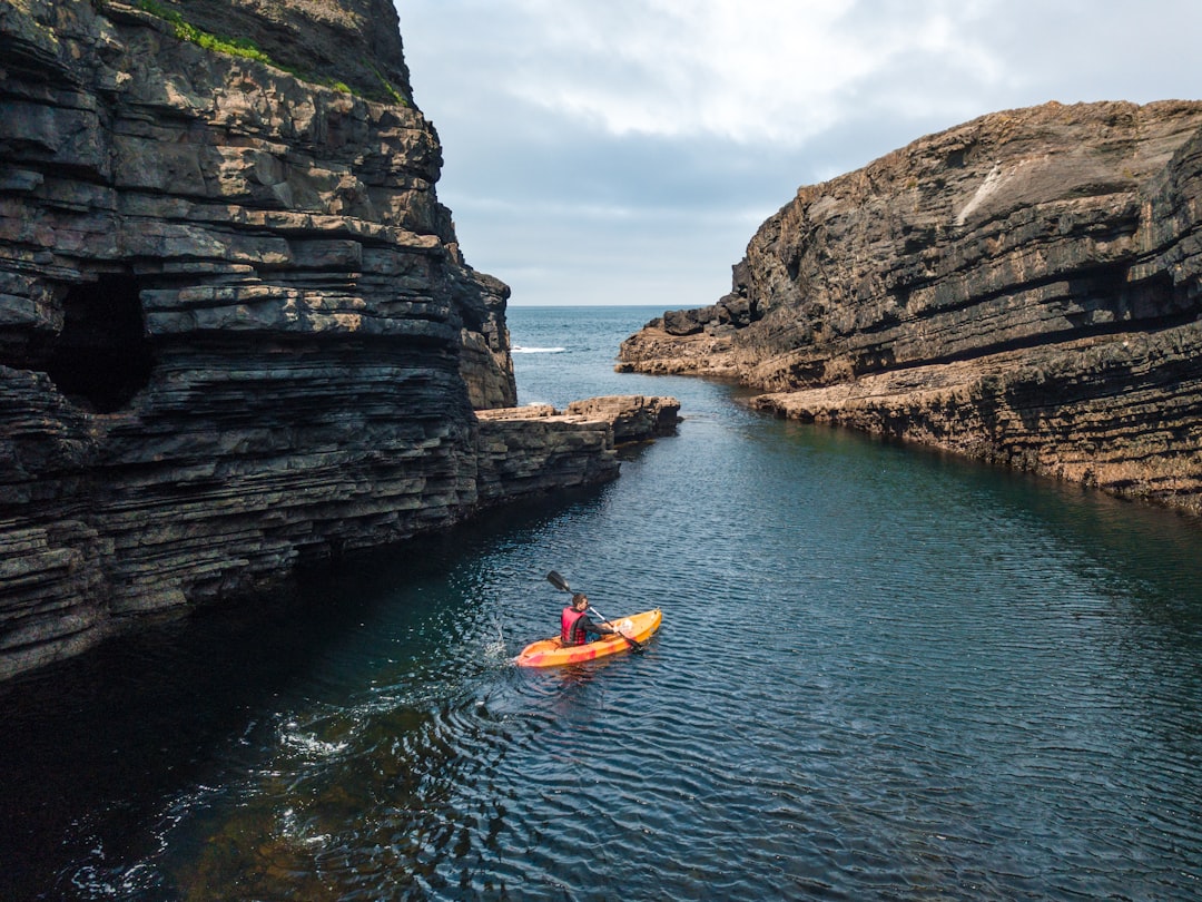 Kayaking along rocky coastline in clear blue water