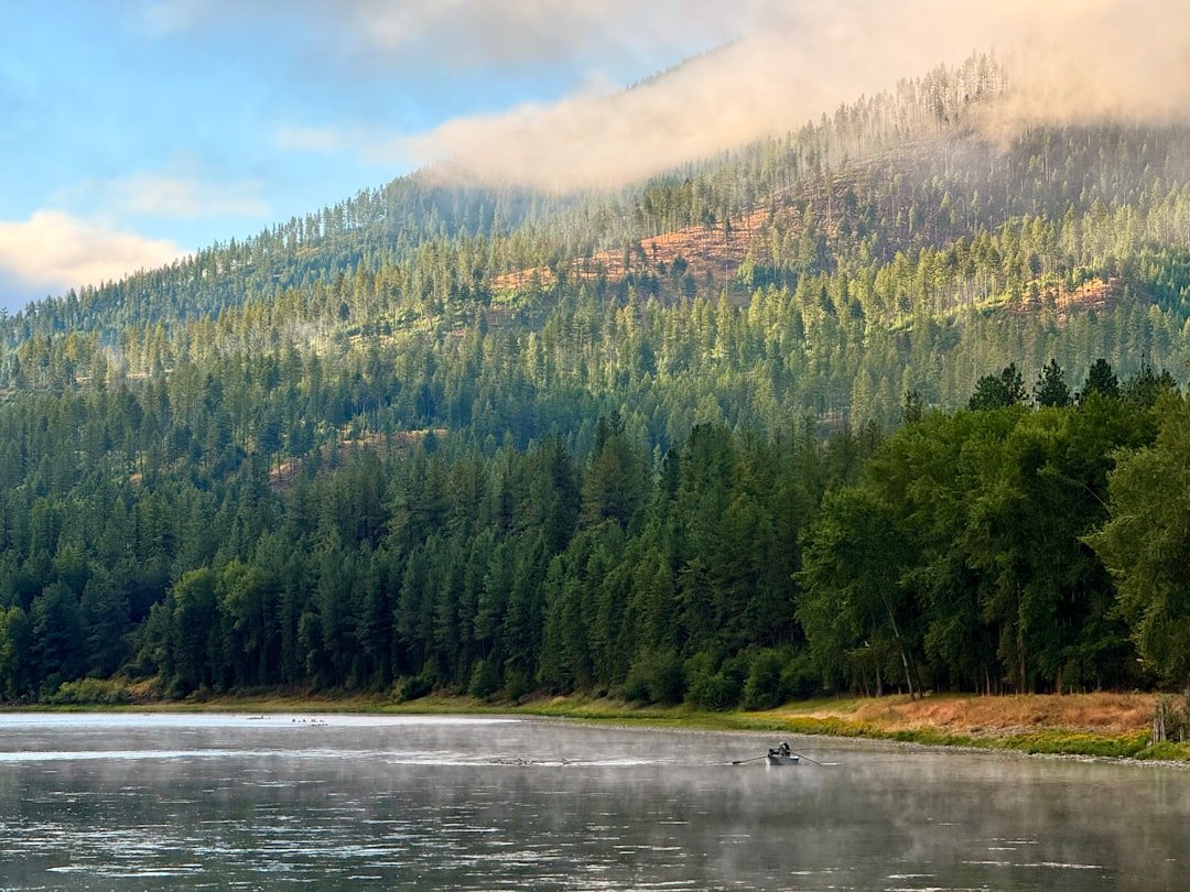 Kayak fishing on a scenic river with mountains in the background