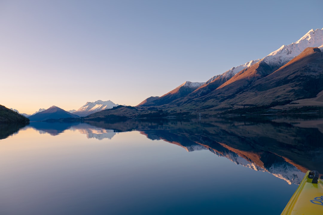 Kayaker paddling across calm lake water in early morning mist