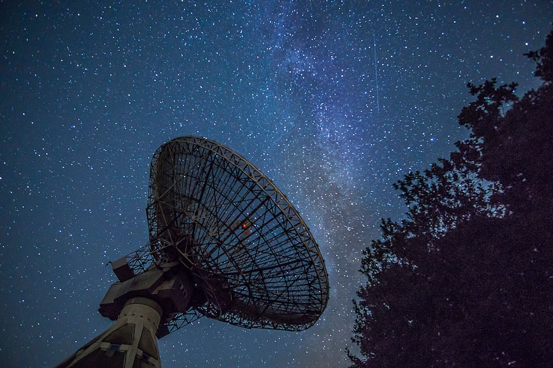 A telescope set up under a starry night sky