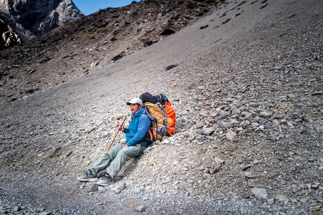 Hiker resting on mountain trail, staying hydrated and prepared