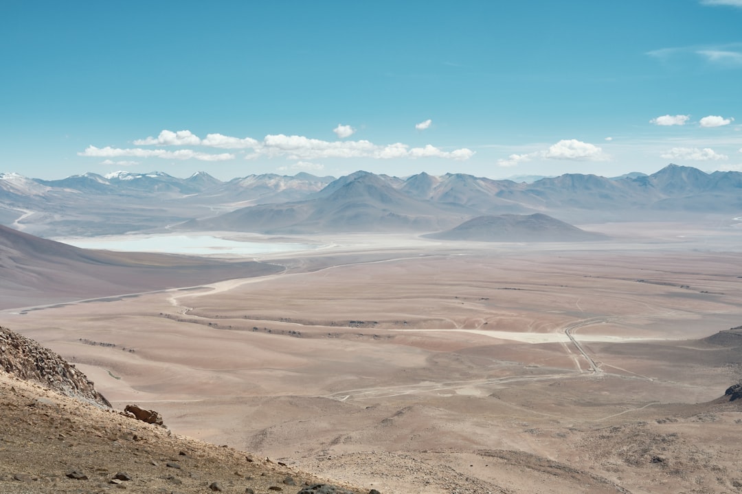 Hiker on a volcanic peak summit trail with panoramic mountain views
