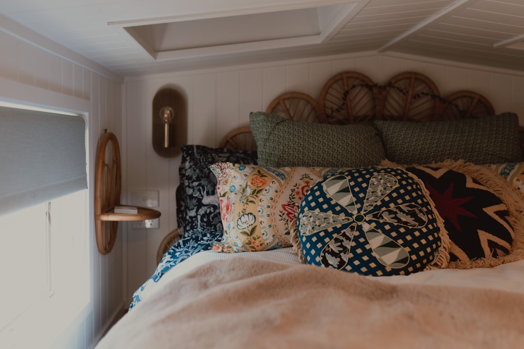 Cozy bed with layered pillows and a window blind