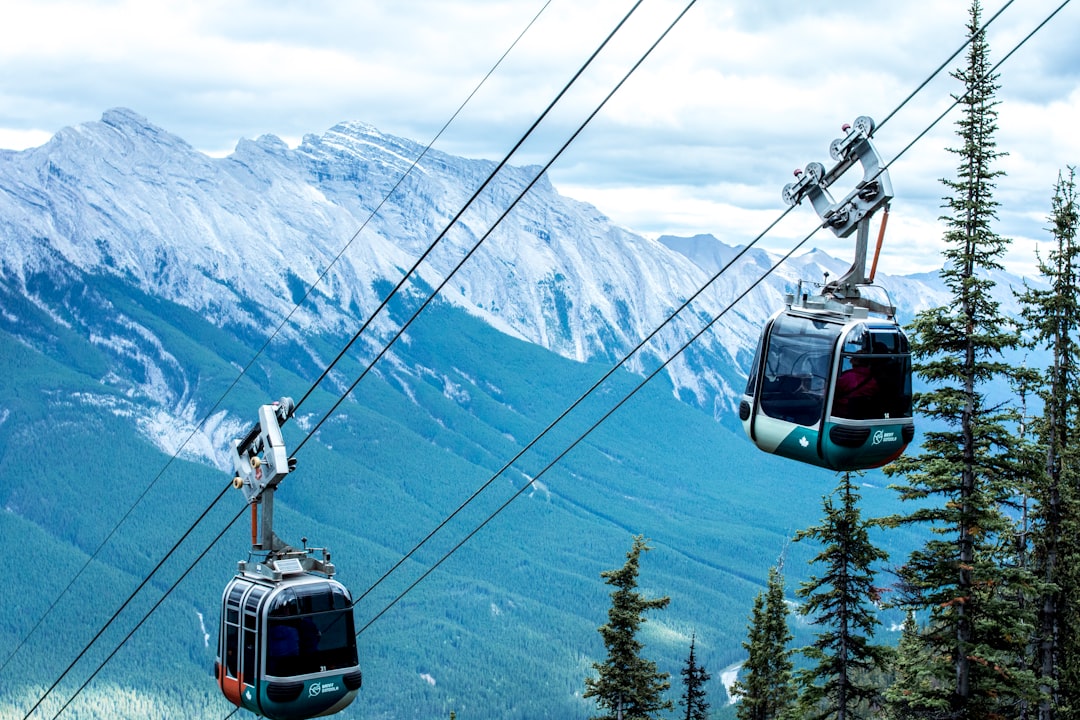 Aerial tramway gondolas rising toward a mountain summit