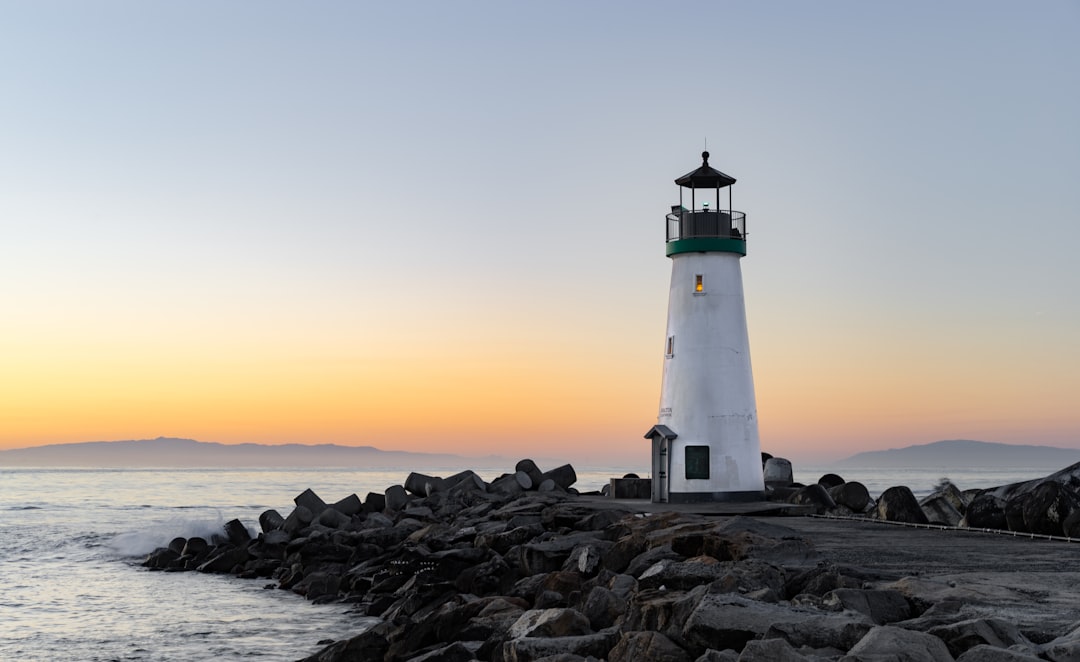 White lighthouse on a rocky breakwater at sunset