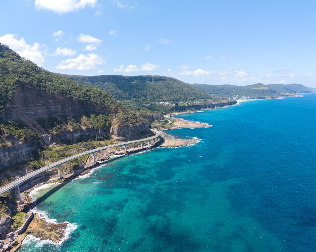 Aerial view of a coastal highway curving along cliffs and turquoise water