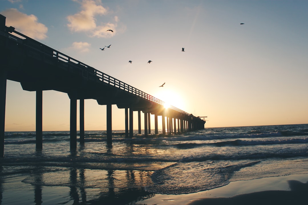 Fishing pier reaching into the ocean at golden sunrise