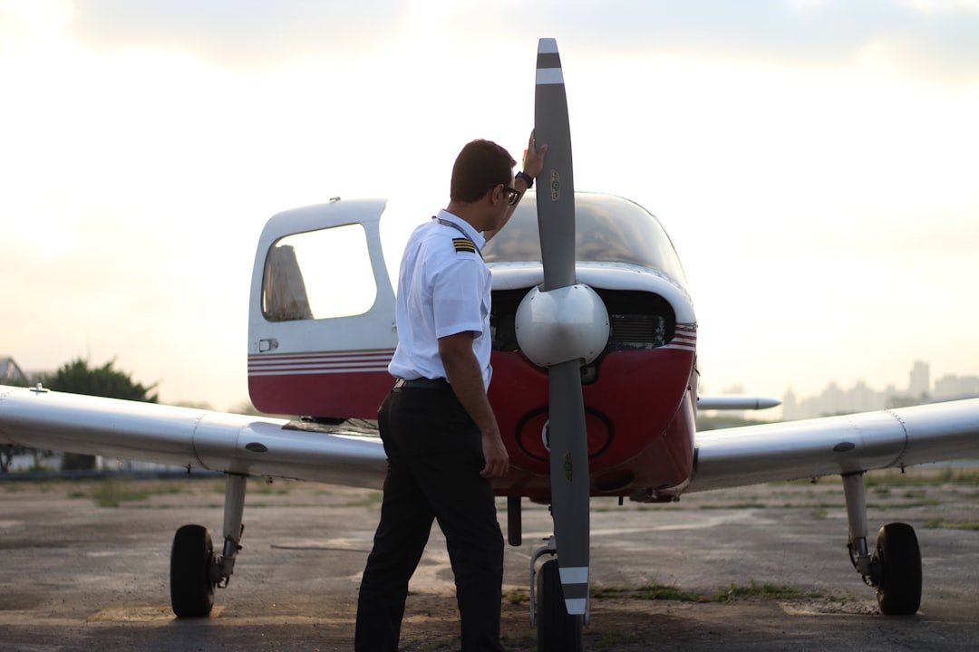 A pilot walking around a small propeller airplane during preflight inspection