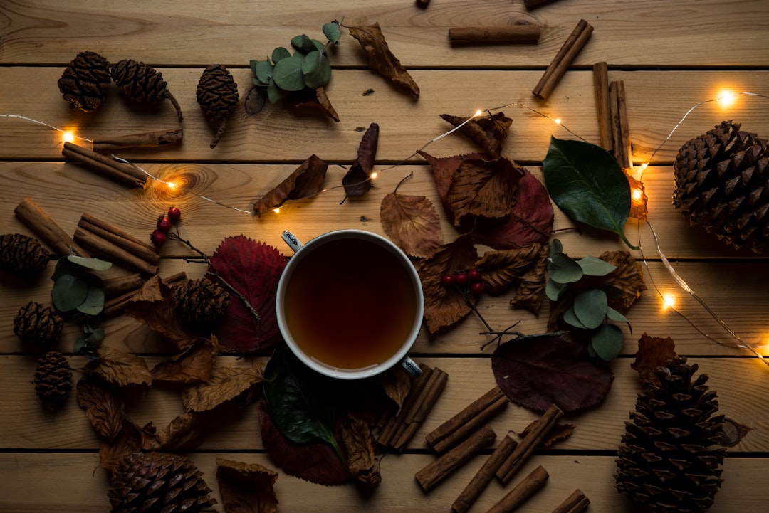 Flat-lay of tea, autumn leaves, pinecones and cinnamon on wood