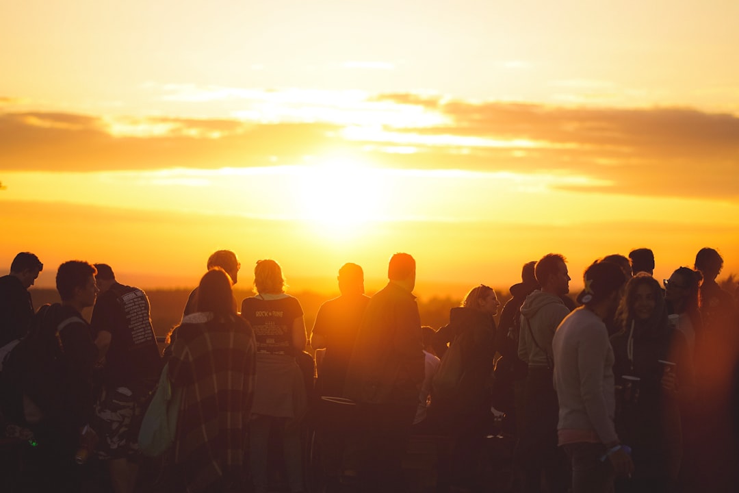 Crowd silhouetted against sunrise at an outdoor event