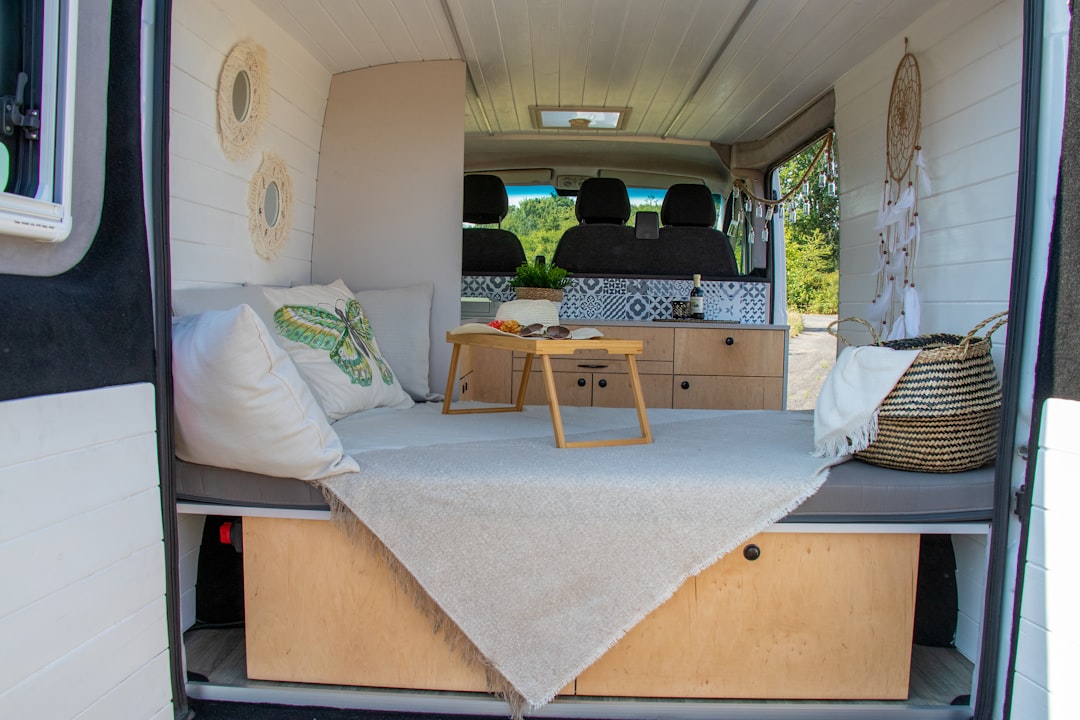 Campervan interior with a made bed, pillows, and storage
