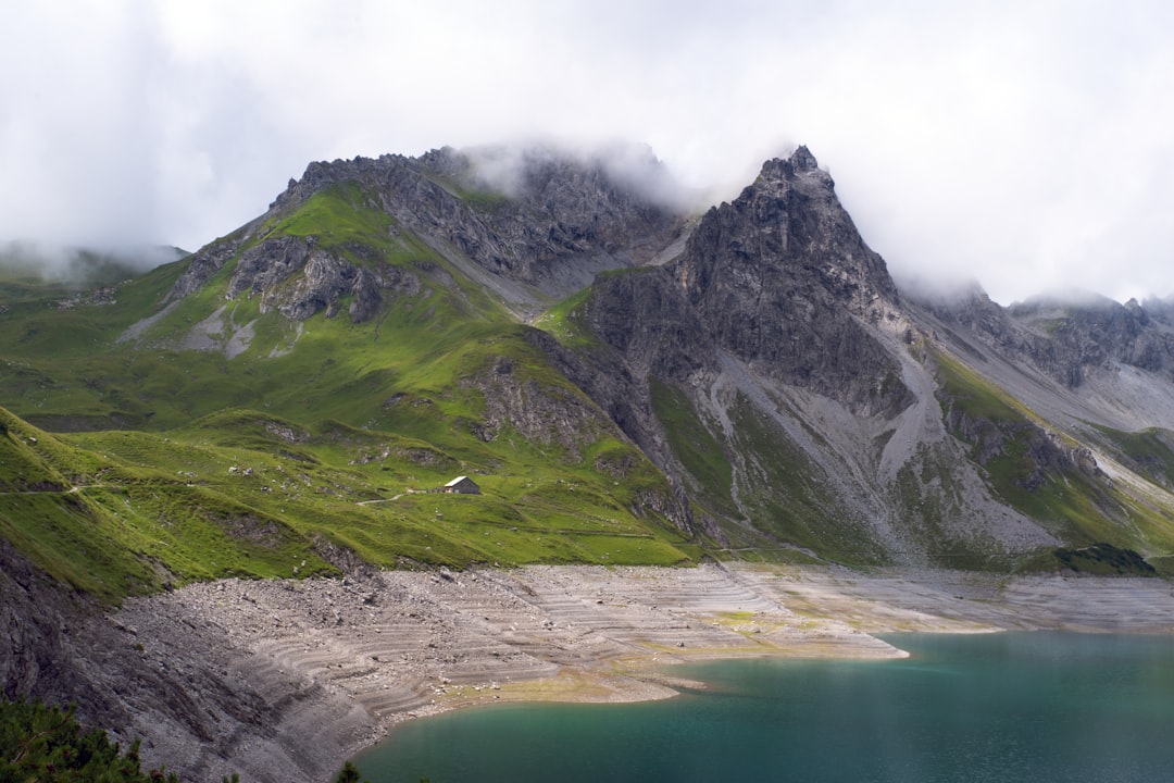 Hiker above a turquoise alpine lake ringed by granite peaks