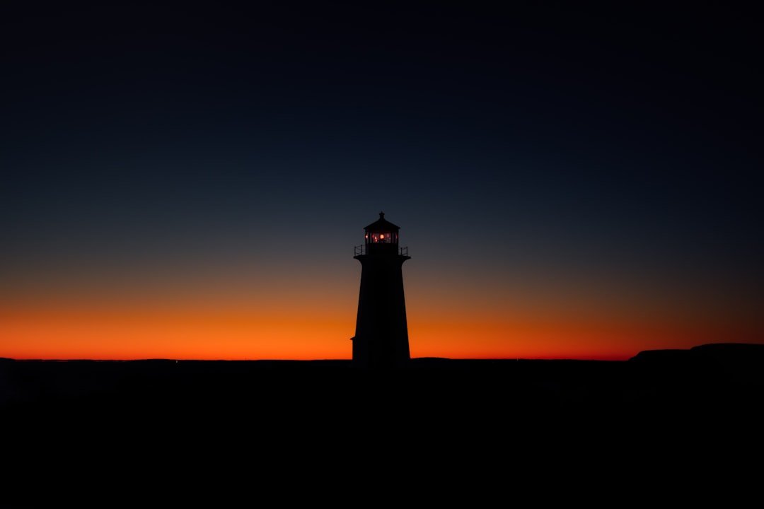 Silhouette of a lighthouse against a vivid sunset sky