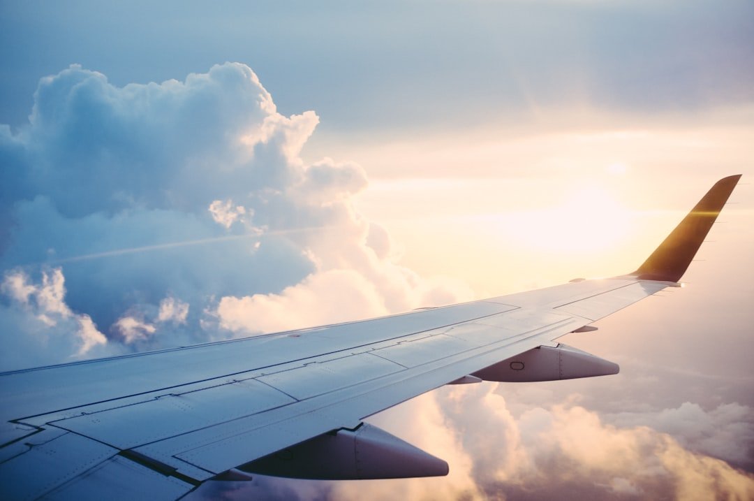 An airplane wing above a layer of clouds at golden hour