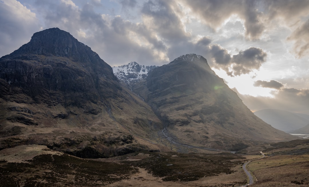 Winding road through a dramatic highland valley under moody clouds