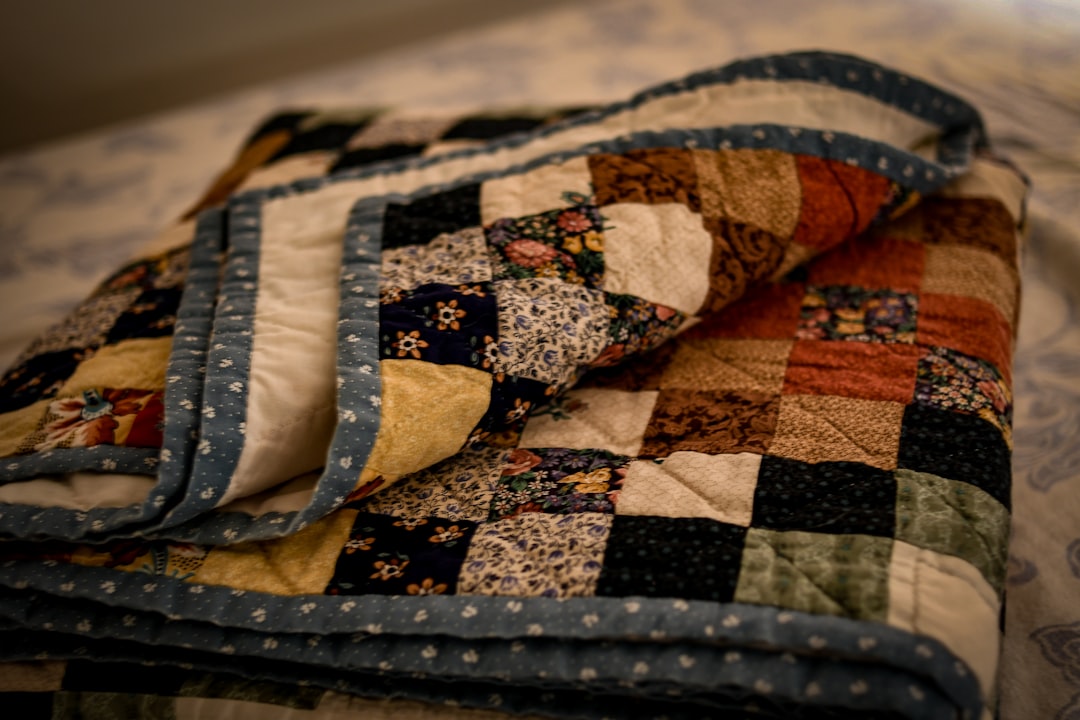 Neatly folded quilt and blankets stacked on a bed