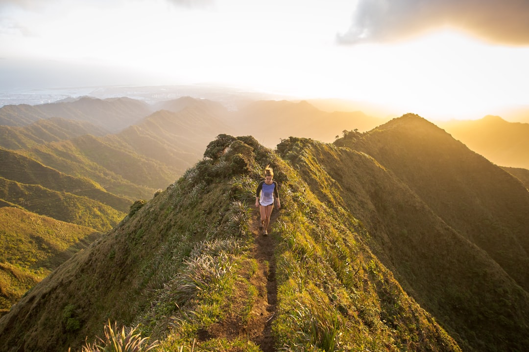 Hiker on a narrow ridge trail with steep drops and mountain views