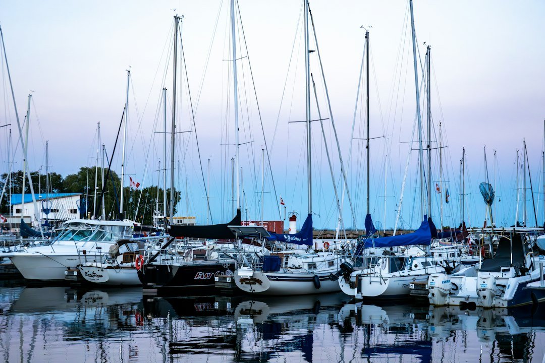 Sailboat marina at dusk with mast lights reflecting on the water