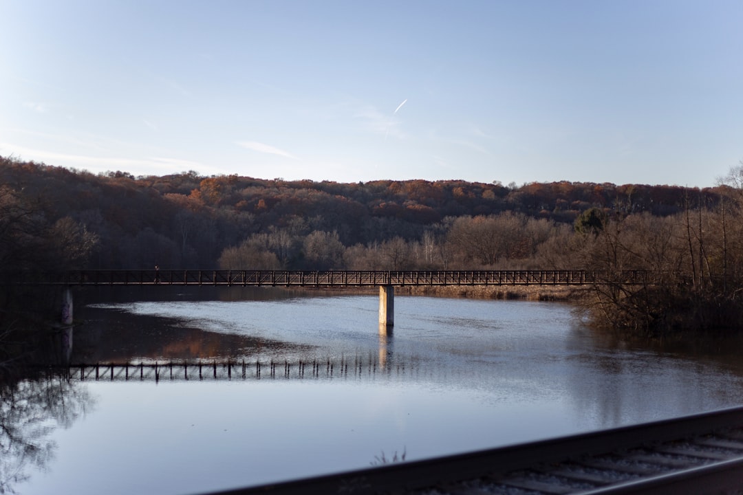 Vintage railroad trestle bridge crossing a calm river between autumn hills