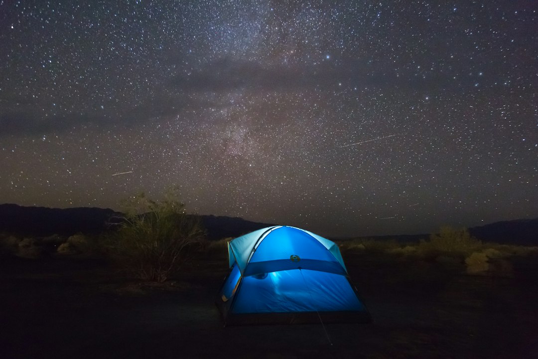 A glowing tent sits under a starry desert sky at a Death Valley campground