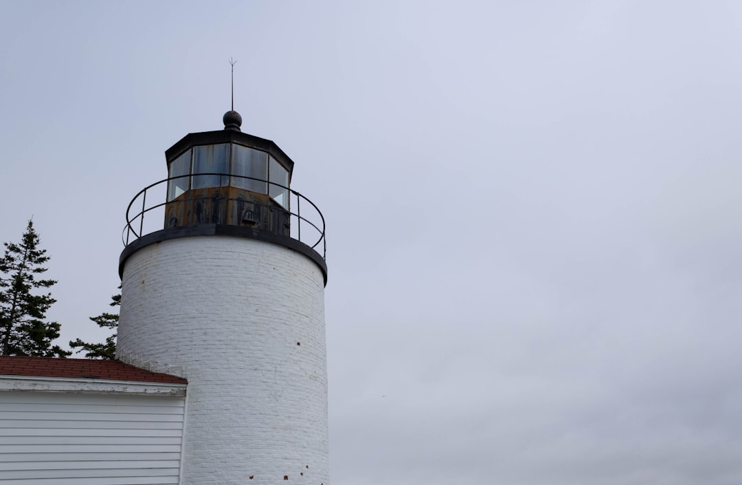 A classic white Maine lighthouse under an autumn sky