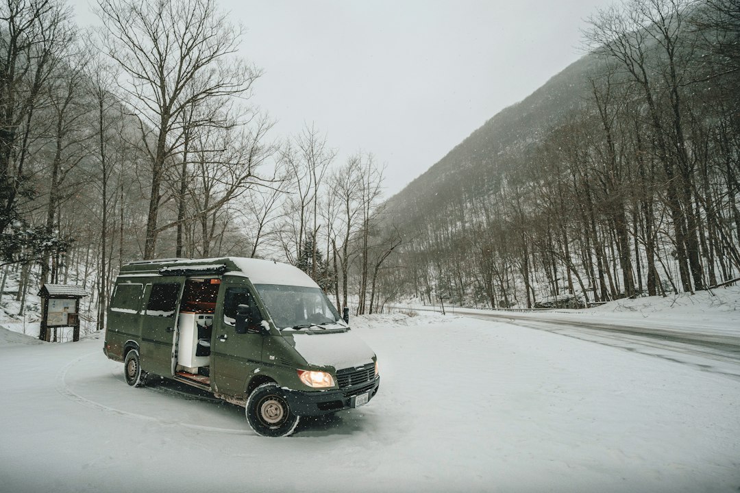Campervan driving a snowy mountain road in falling snow
