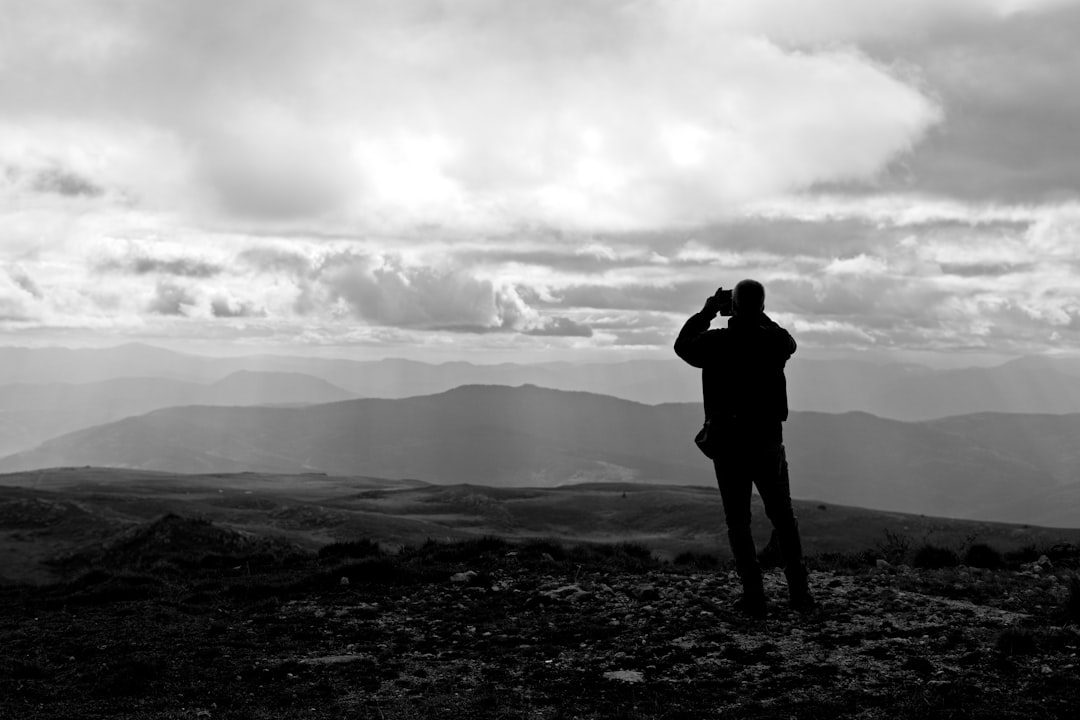 Silhouette of a hiker scanning a mountain ridgeline with binoculars