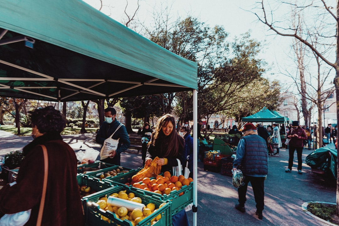 Open-air farmers market with crates of fresh citrus under green canopies