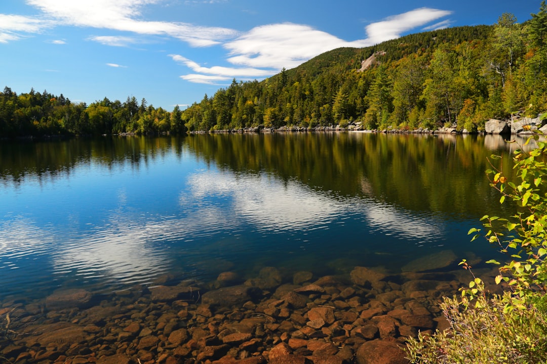 Calm Adirondack lake in autumn with rocky shore and reflections