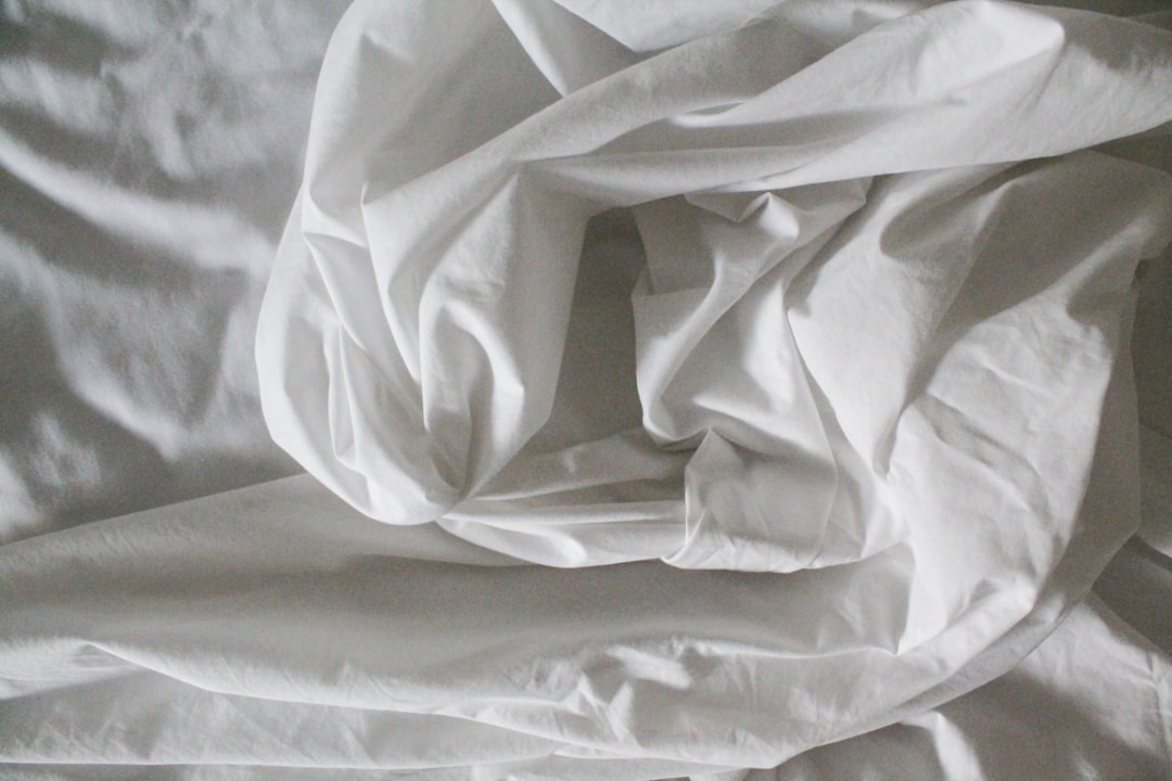 Rumpled white bed sheets in soft morning light