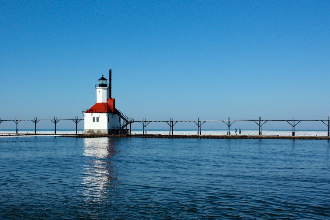 White lighthouse with red roof standing over open water