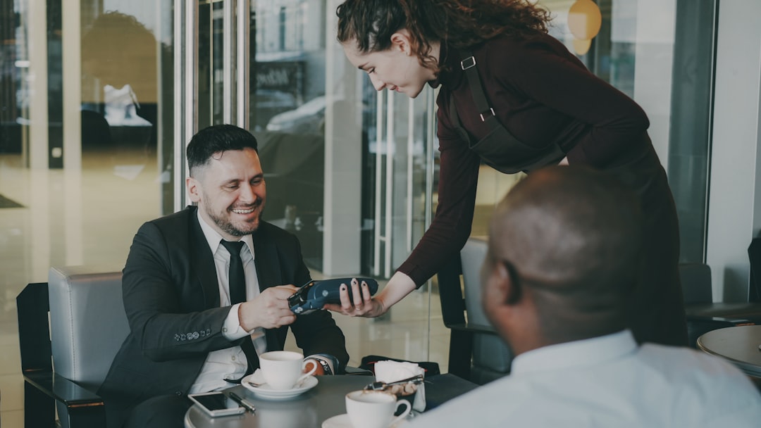 Server processing a card payment at an outdoor cafe table