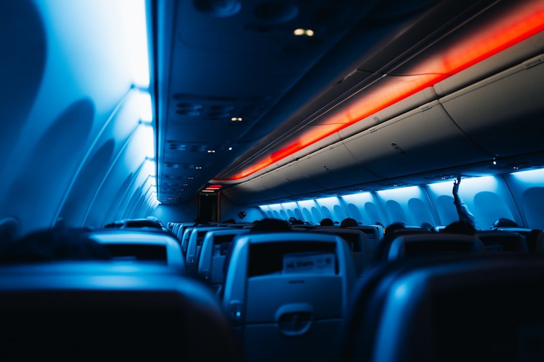 Dimly lit airplane cabin interior at night with ambient lighting and seated passengers