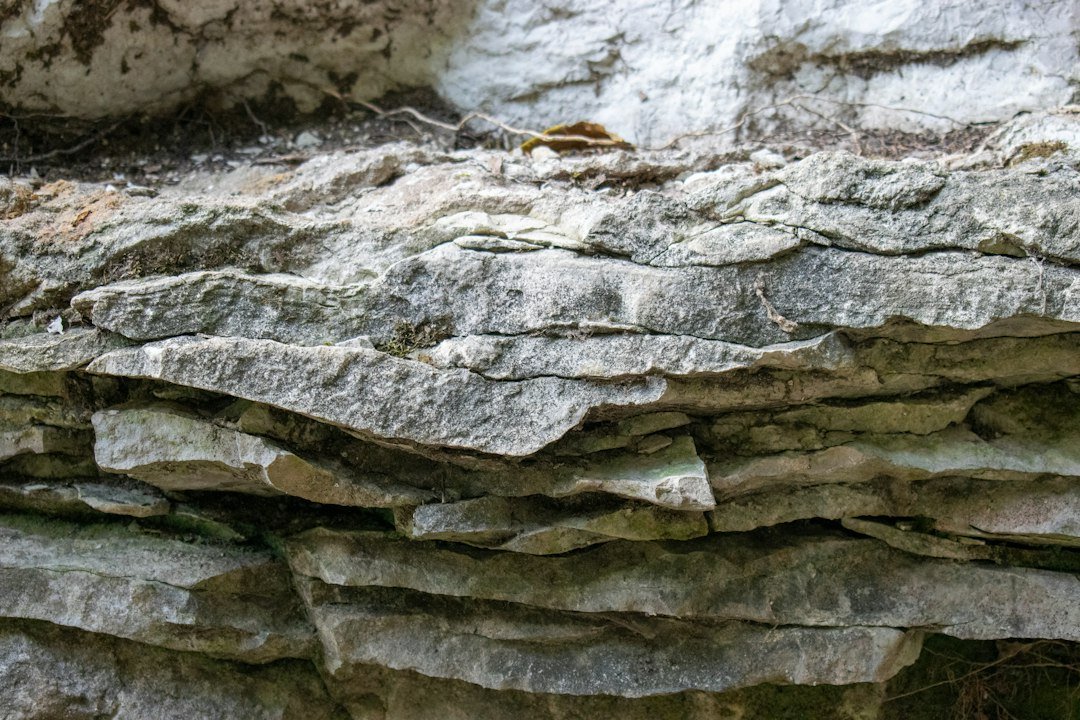 Layered bands of pale limestone rock in a cliff face above water