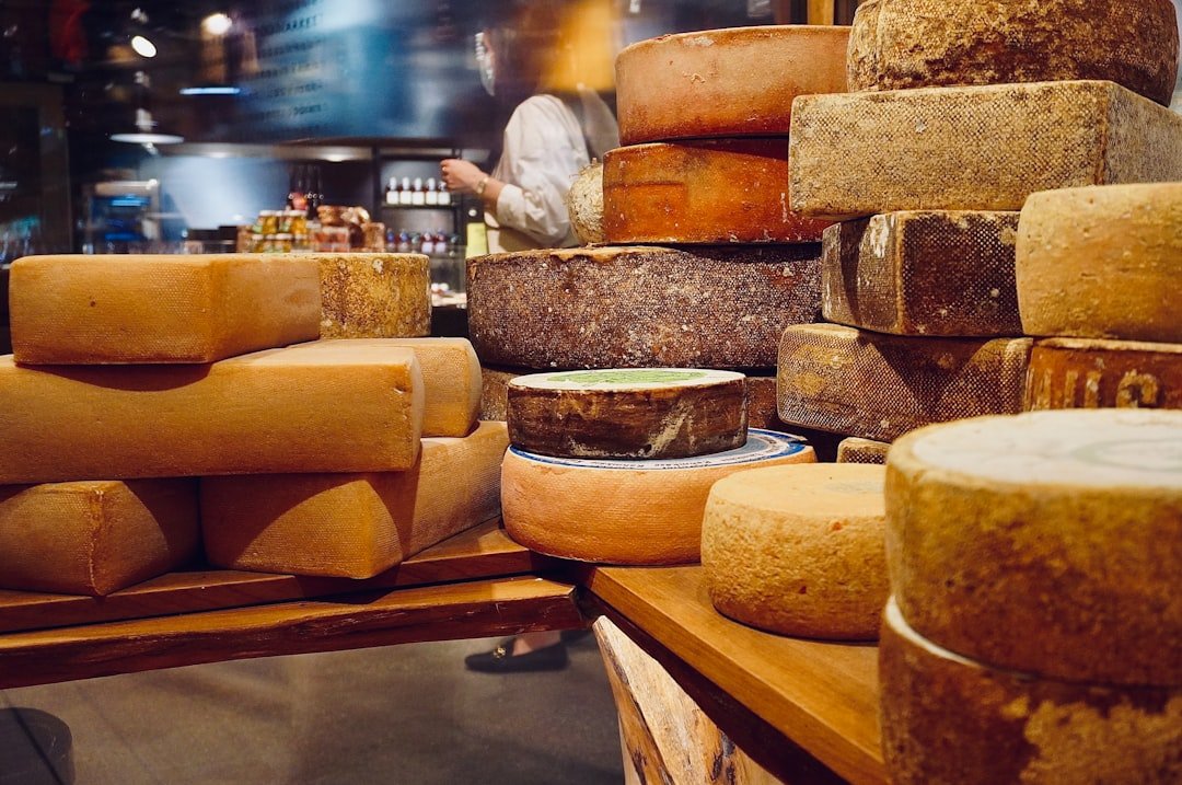 Wheels and blocks of cheese stacked on wooden shelves