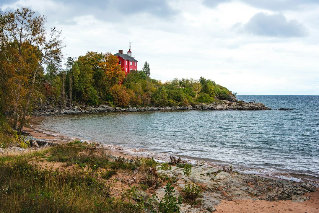 Lighthouse standing on a rocky bluff above an autumn lake