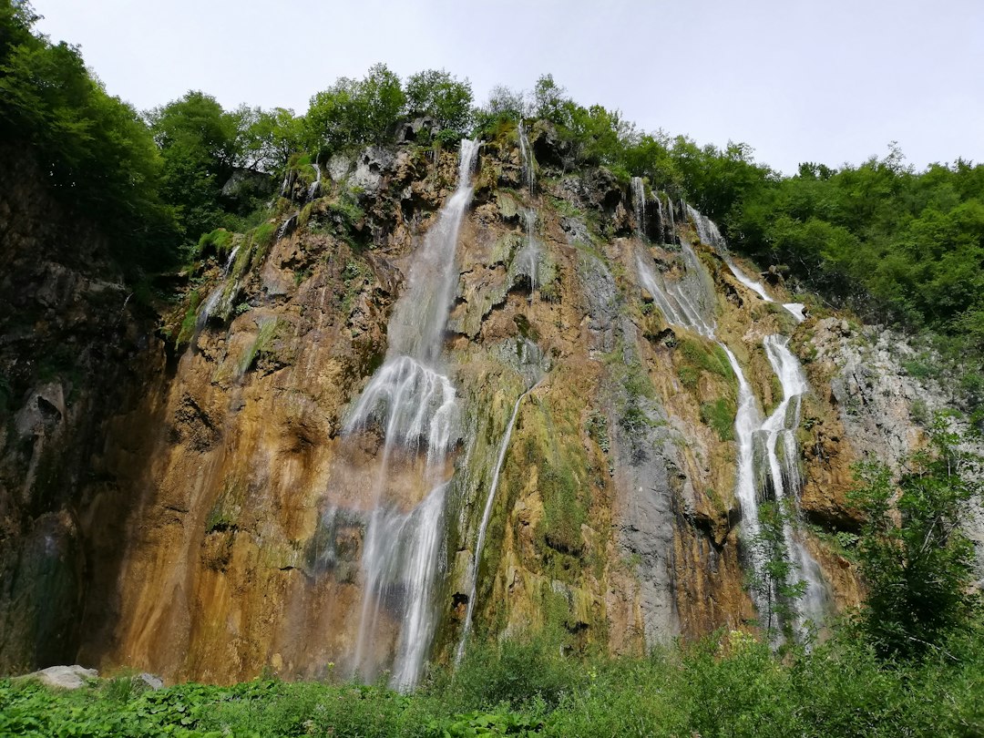 A multi-stream waterfall pouring down a forested rock cliff