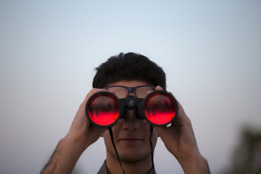 A visitor scanning the prairie through compact binoculars