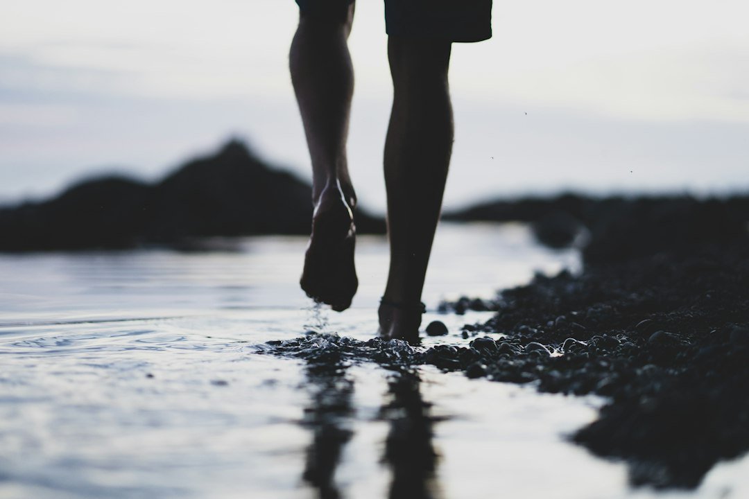 Bare feet walking through shallow shoreline water