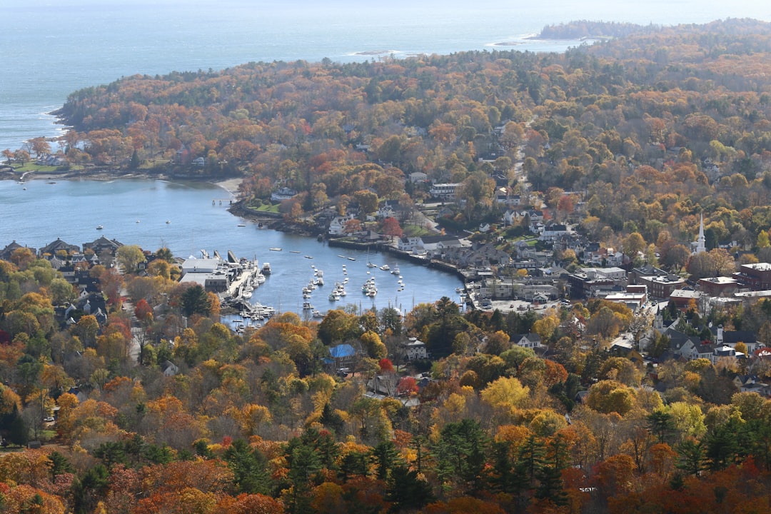Aerial view of a coastal New England town with harbor and fall foliage